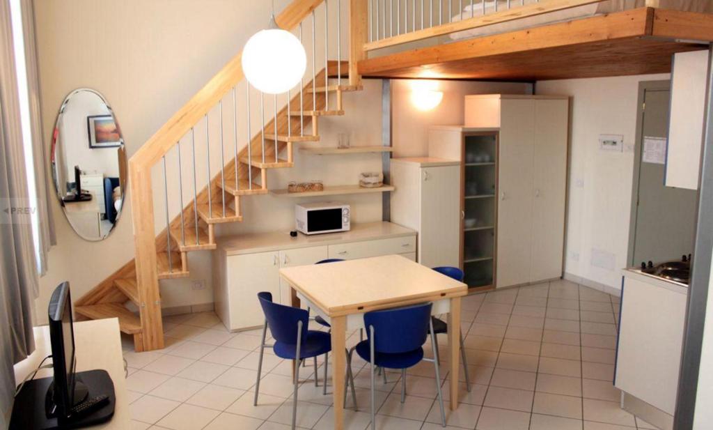 a kitchen and dining room with a table and blue chairs at Residence Villa Marina in Marina di Ravenna