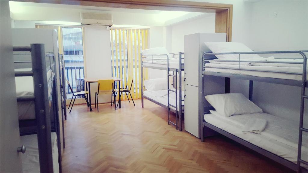 ブカレストにあるSleep Inn Hostelの二段ベッド3台、テーブル、椅子が備わる客室です。