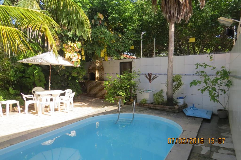 a pool with a table and chairs and an umbrella at Casa Tamandaré in Tamandaré