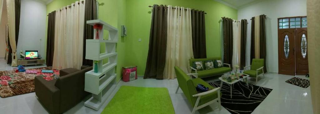 salon z zielonymi ścianami i kanapą w obiekcie Airport Kelantan HOMESTAY & TRANSIT ROOM w mieście Kota Bharu