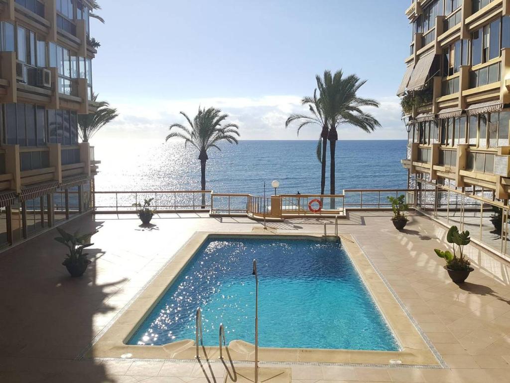 a swimming pool with the ocean in the background at Primera línea de playa in Marbella