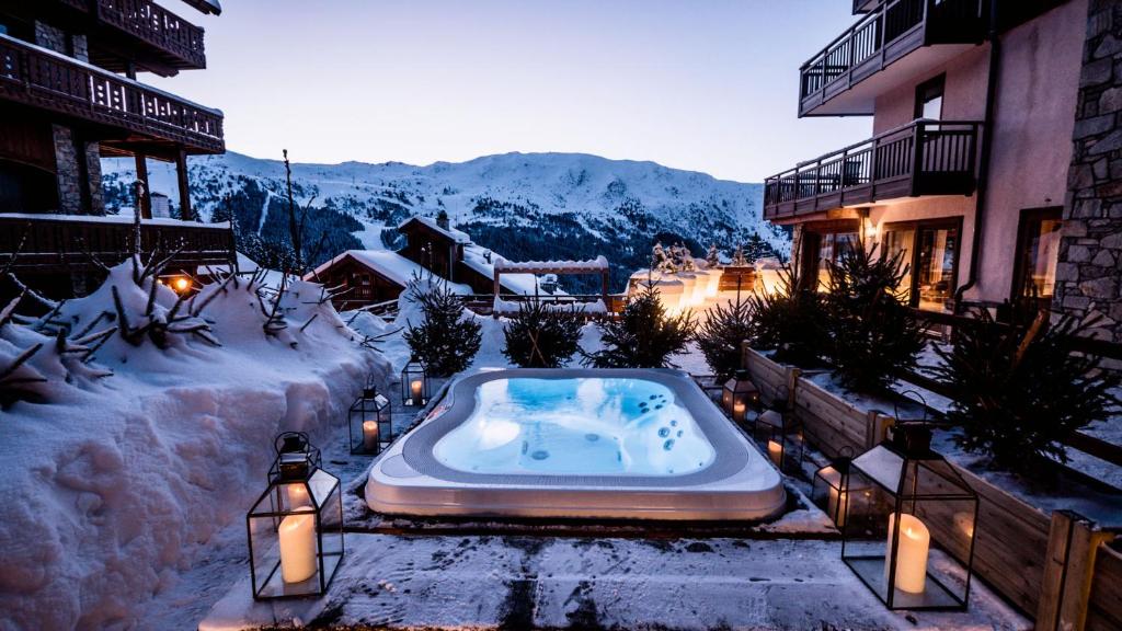 a jacuzzi tub in the snow next to a building at Hotel & Spa Merilys in Méribel