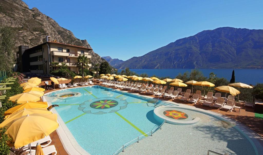 una piscina con sombrillas y sillas y un hotel en Hotel Ilma Lake Garda Resort en Limone sul Garda
