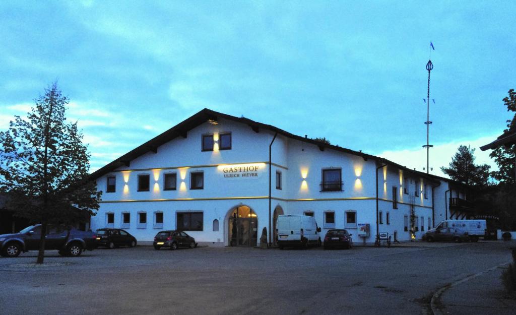 un gran edificio blanco con coches estacionados frente a él en Gasthof Ulrich Meyer, en Landshut