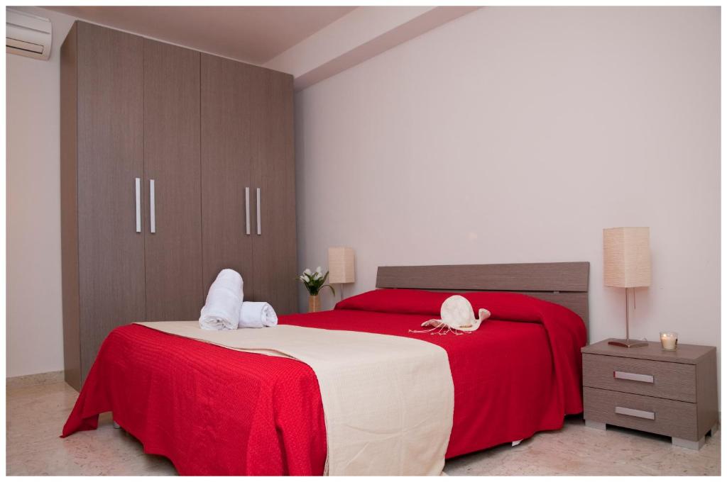 a bedroom with a red and white bed with towels on it at Appartamenti Sant' Andrea in Trapani