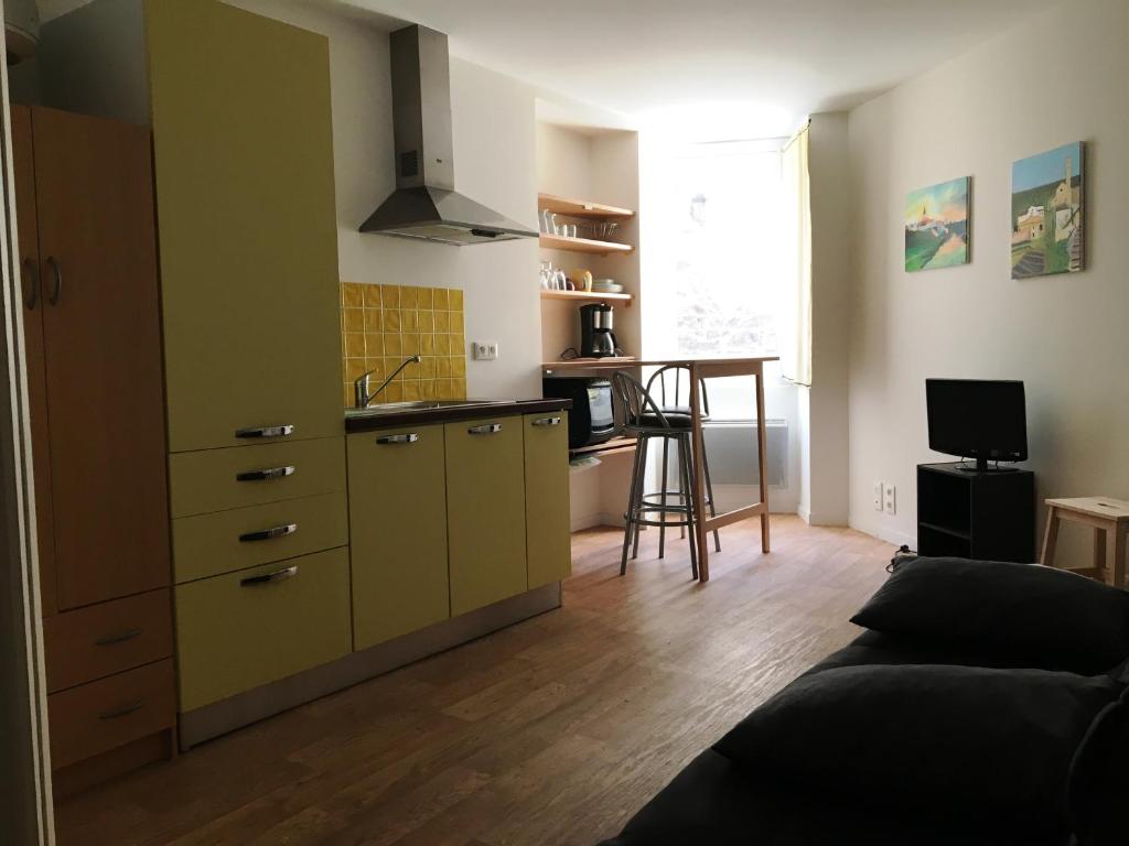 une cuisine avec des armoires jaunes et un salon dans l'établissement Studio Centre Granville, à Granville