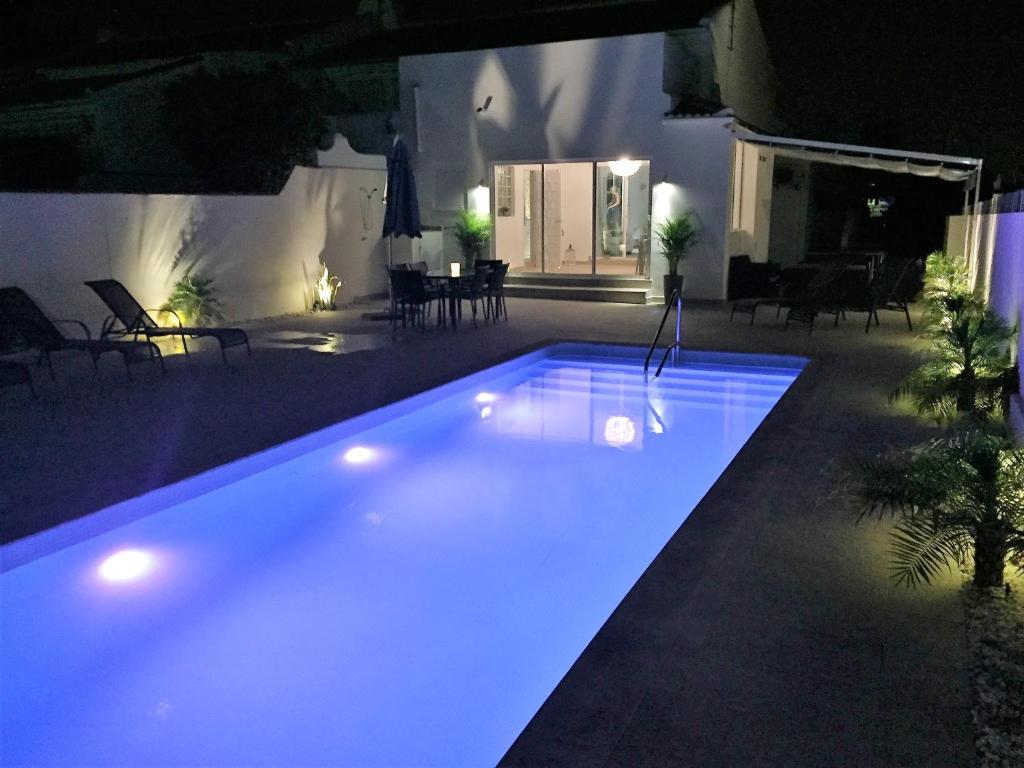 une piscine avec des lumières bleues dans une arrière-cour dans l'établissement Campoamor Villa & Private Pool, Garden & Roof Terraces Distant Sea Views, à Playas de Orihuela