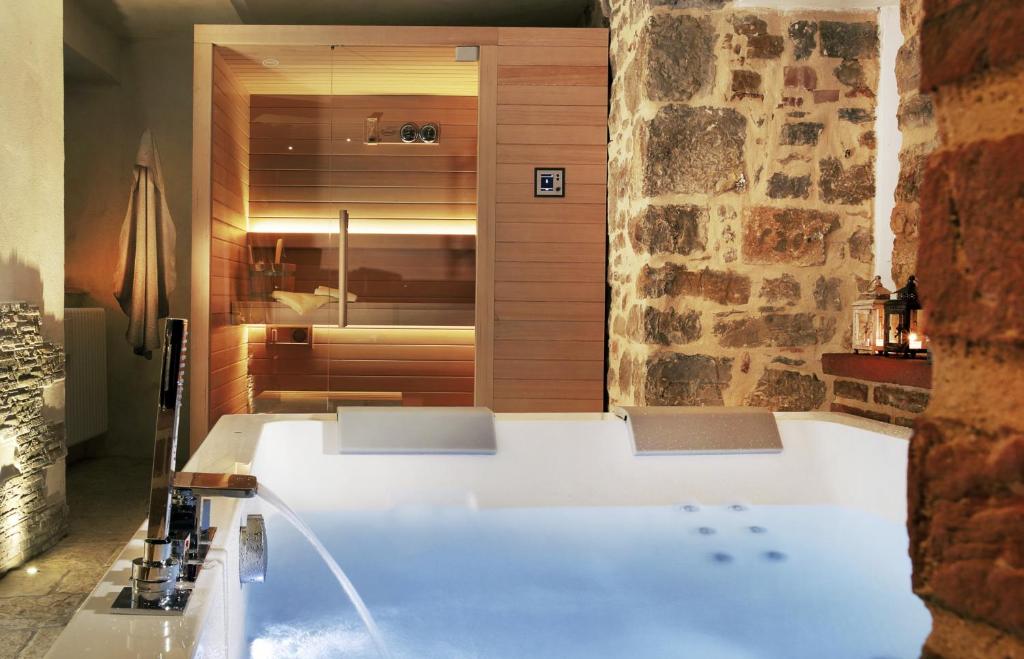 una grande vasca da bagno in una stanza con parete in pietra di Villa Sofia & Spa a Gaiole in Chianti