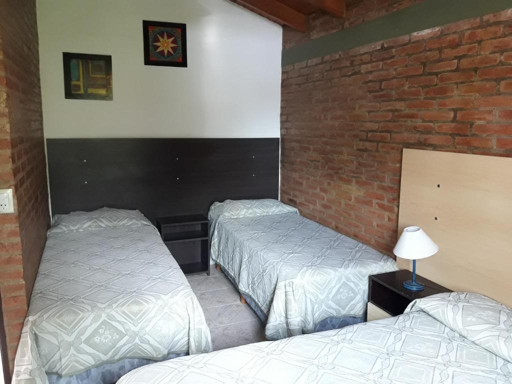Habitación con 2 camas y pared de ladrillo en Ariel Reynoso - Departamento Planta Alta en Mina Clavero