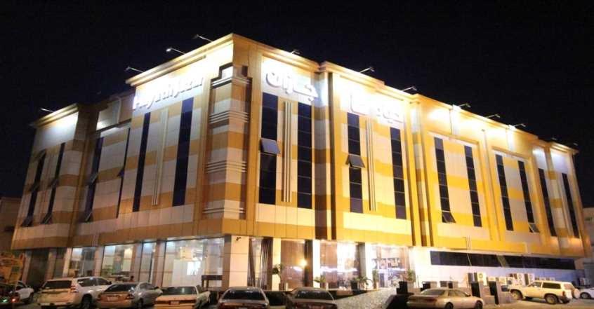 a large building with cars parked in front of it at Hayat Jazan Furnished Units in Jazan