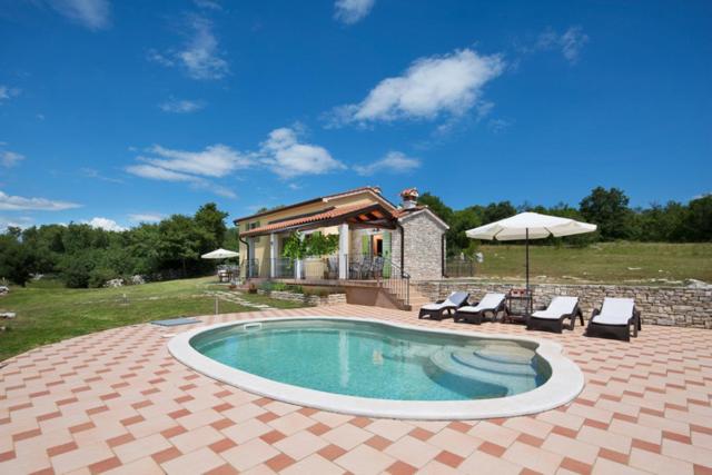 a pool with chairs and an umbrella and a house at Villa Valmont in Labin