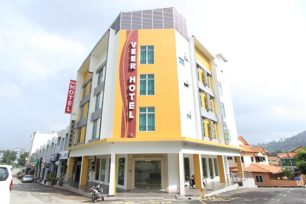 a yellow and white building with a sign on it at Veer Hotel in Kuantan