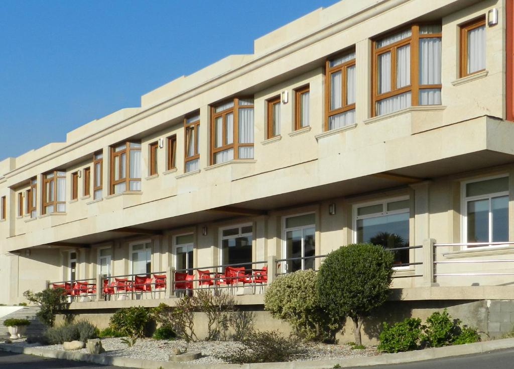 a building with red chairs on the balcony at Hotel Costa Verde in Villadesuso