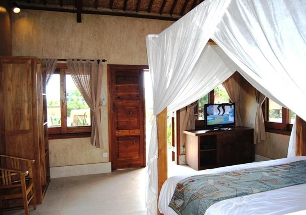 a bedroom with a bed and a television in it at Three Monkeys Villas in Uluwatu