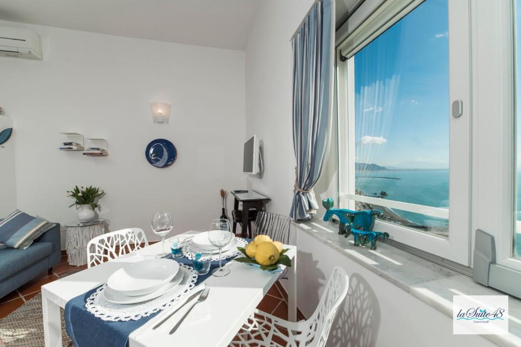 a white dining room with a table and a large window at La Suite 48 in Vietri sul Mare