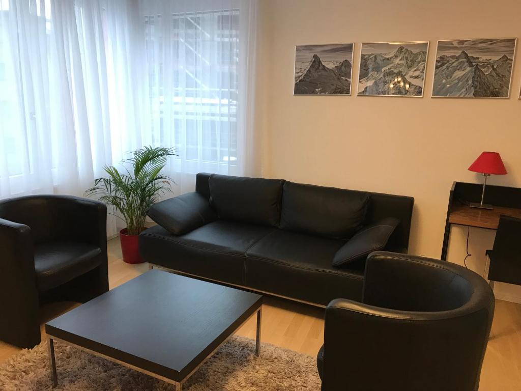 a living room with a black couch and two chairs at Close to Zürich centre and Airport in Kloten