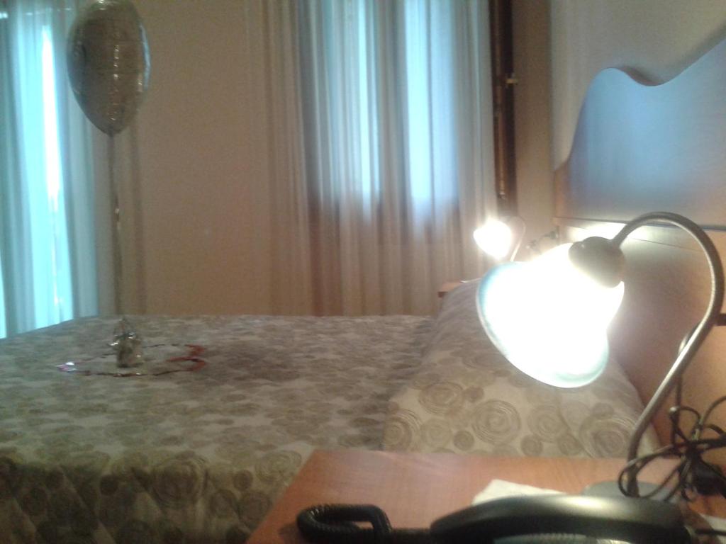 1 dormitorio con 1 cama con mesa y lámpara en Locanda "Alla Rosa", en Lusiana