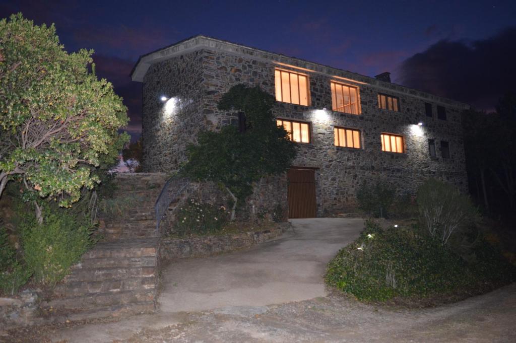 una casa de piedra con luces encendidas por la noche en Las Estrébedes Casa Rural, en Caminomorisco