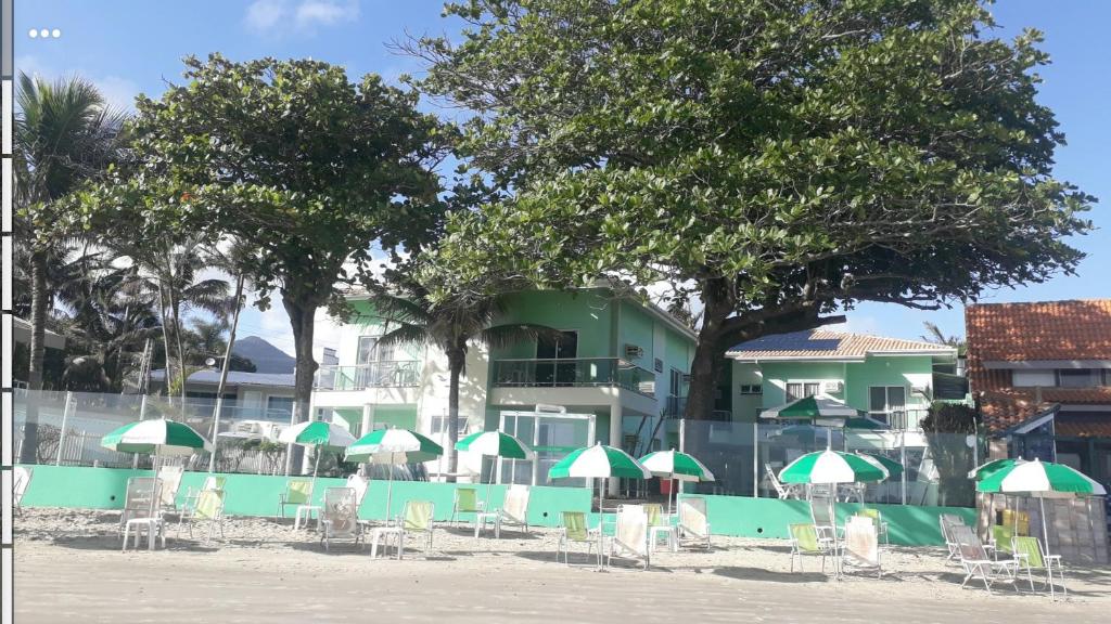 eine Gruppe von Stühlen und Sonnenschirmen vor einem Gebäude in der Unterkunft Pousada Vila Verde in Porto Belo