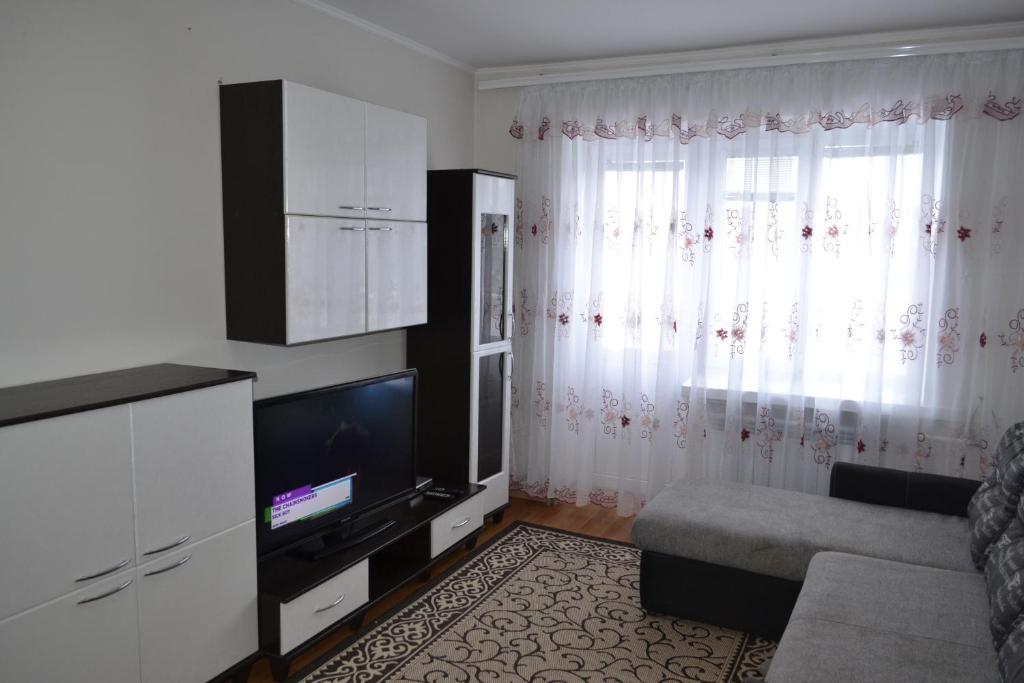 a living room with a couch and a tv and curtains at Apartment on Kniaziv Koriatovychiv 9 in Kamianets-Podilskyi
