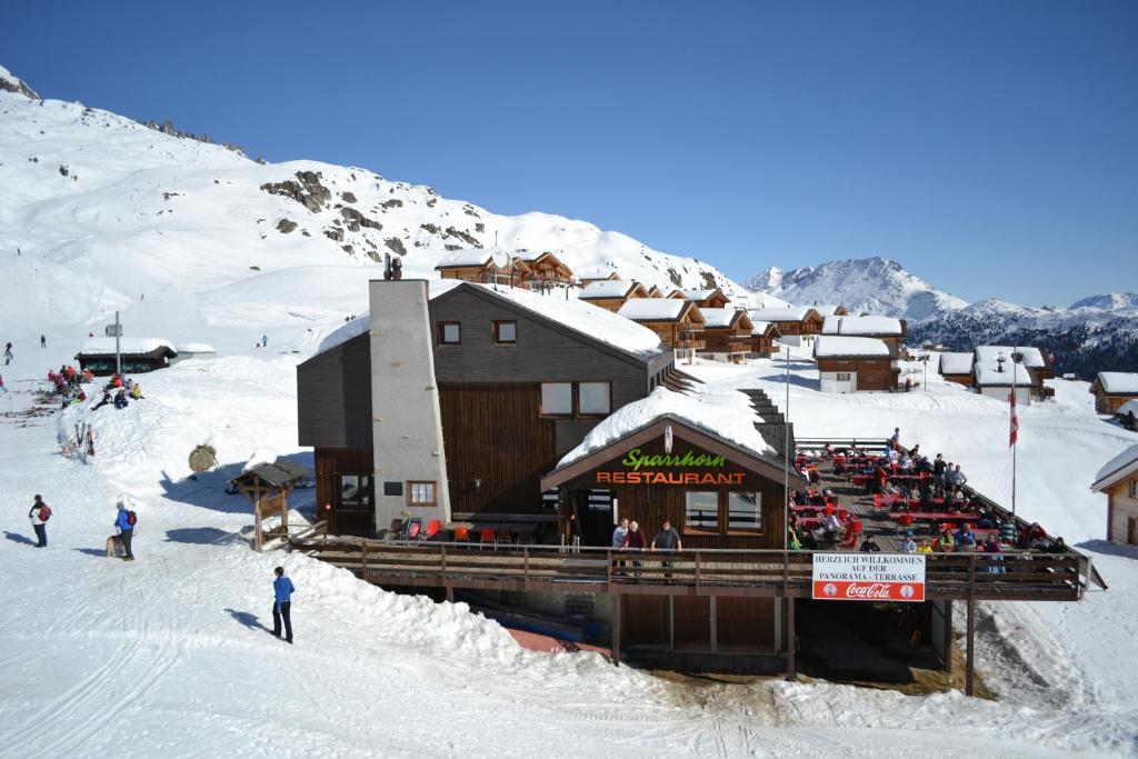 a ski lodge on a snow covered mountain with people at Hotel Sparrhorn in Belalp