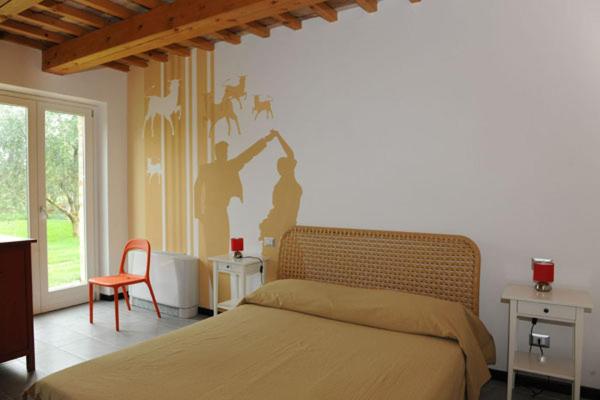 Casale Papa Country Village في لوريتو: غرفة نوم بسرير وجدار مع لوحة للناس