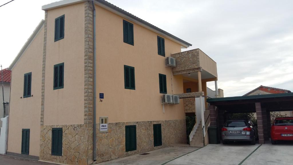 a building with a car parked in front of it at Apartmani Jakovljevic in Murter