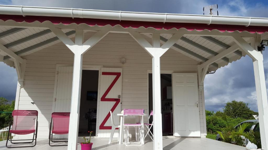 une terrasse couverte avec des chaises roses et une table. dans l'établissement Fleur d'Hibiscus, à Saint-Louis