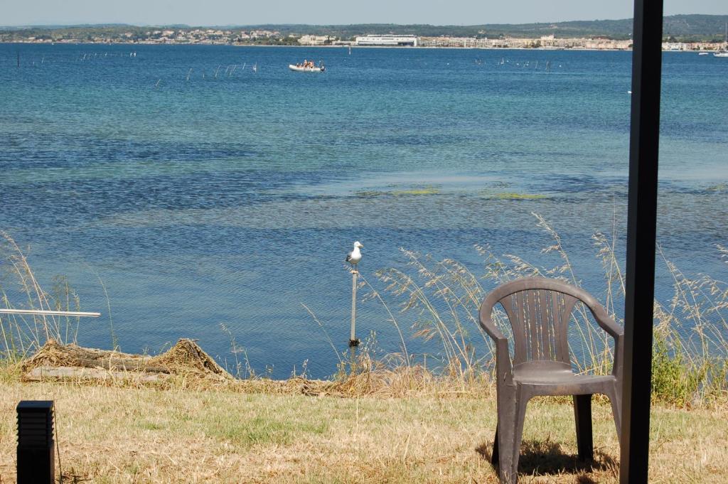 una silla sentada frente a un cuerpo de agua en maison atypique les pieds dans l'eau, en Sète
