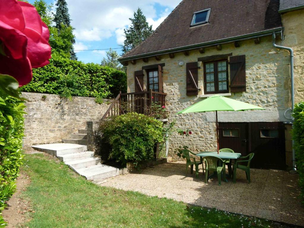 une table avec un parasol vert devant une maison dans l'établissement Petites maisons avec piscine, à Sarlat-la-Canéda