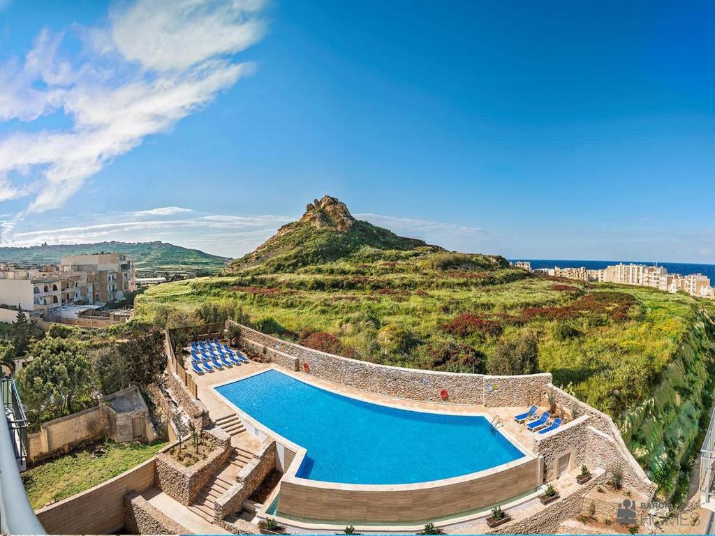 een zwembad op de top van een heuvel met een berg bij Azure Cottage in Żebbuġ