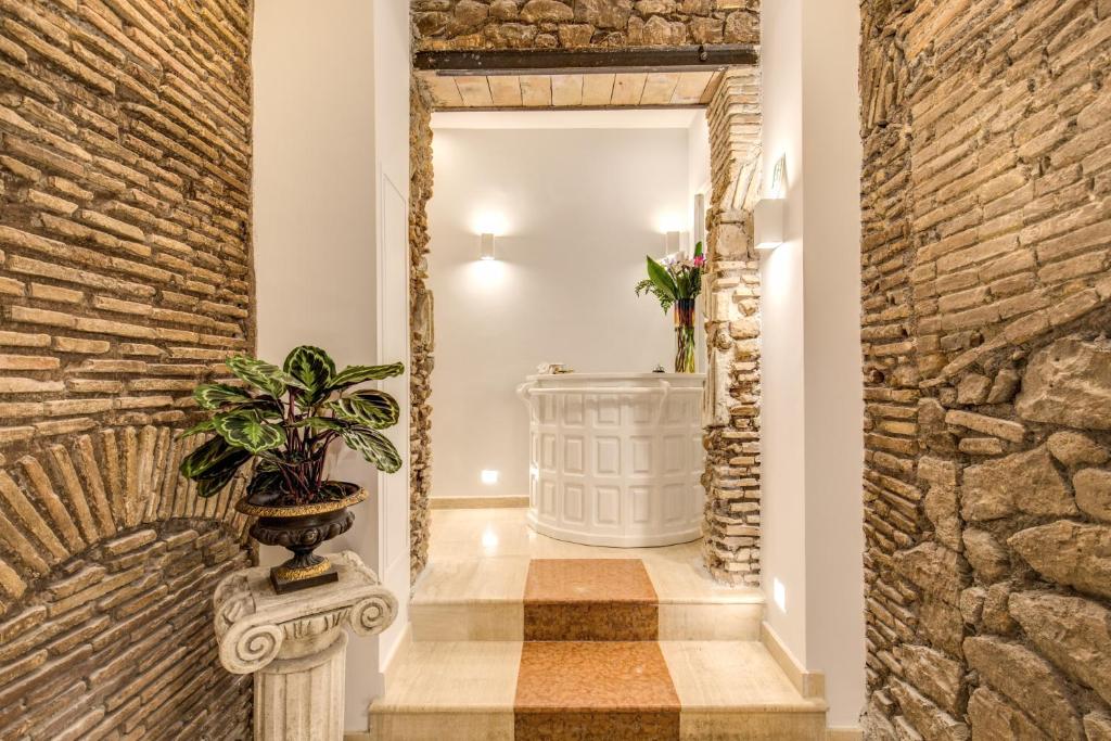 un corridoio con un muro di pietra e una pianta in vaso di Pantheonview - Luxury Suites a Roma