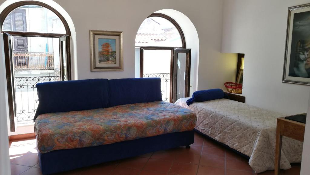 ein Wohnzimmer mit einem Sofa und 2 Fenstern in der Unterkunft Piccolo Casale in Milazzo