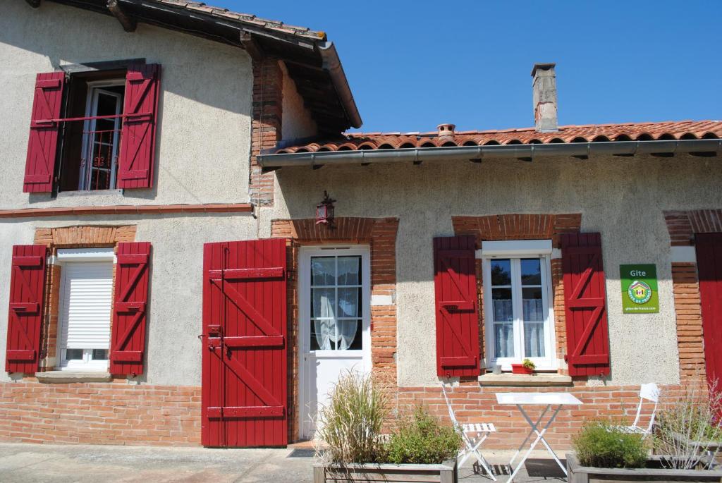 una casa con persiane rosse e finestre di Gîte d'en Pouillac a Saint-Thomas