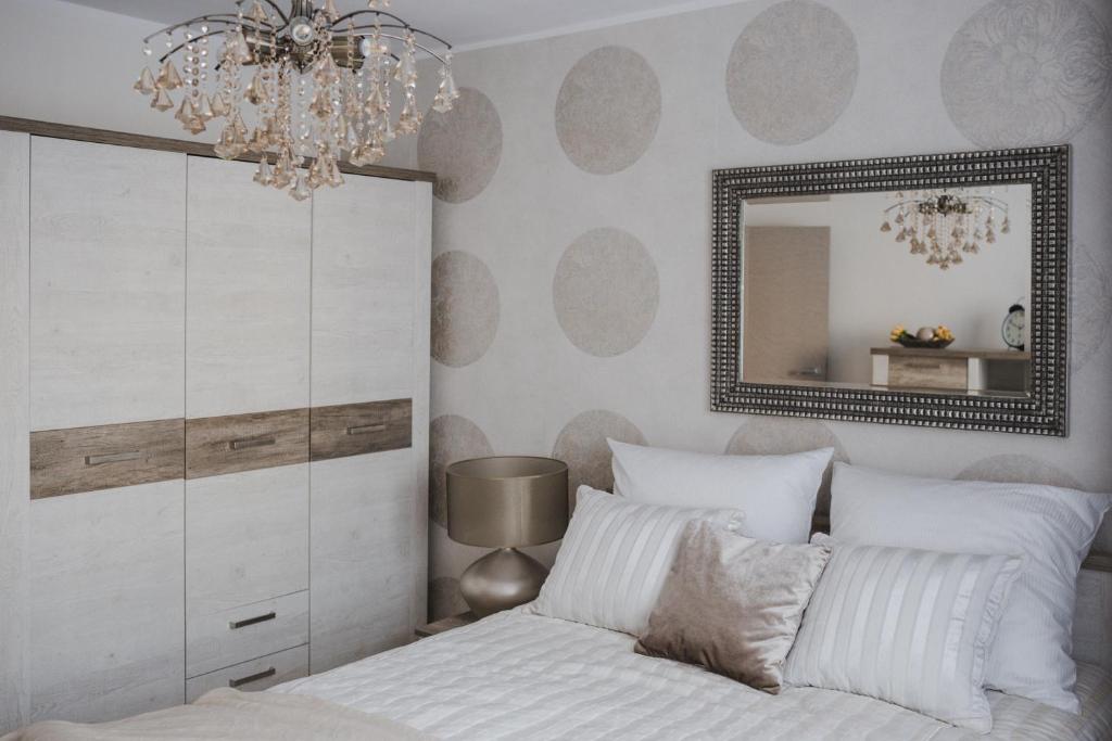a bedroom with a bed with a mirror and a chandelier at Apartament Hubalczyków in Słupsk