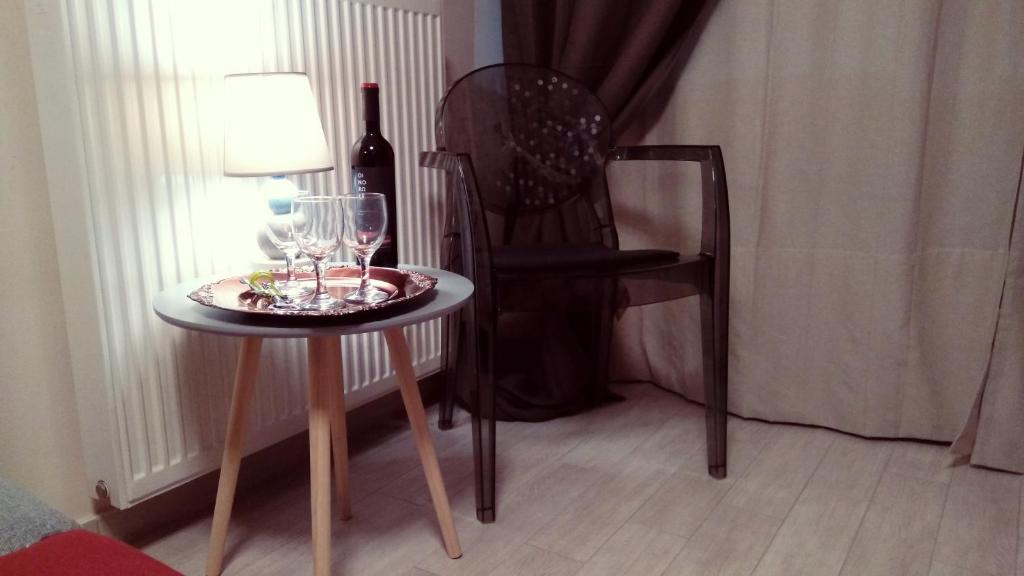 a table with a bottle of wine and a chair at Decosuite Junior Apartments in Kalabaka