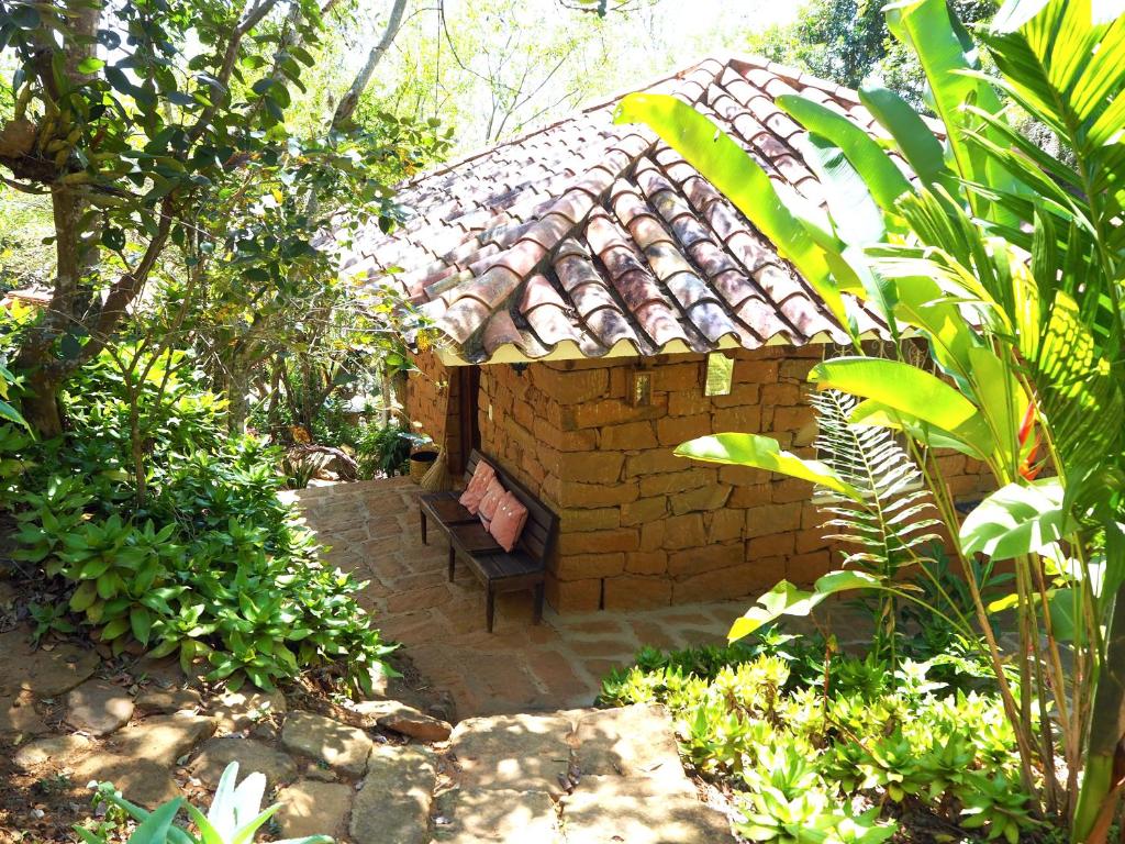 un pequeño edificio de ladrillo con un banco en un jardín en La Cabana de los Novios By Casas del Sur, en Barichara
