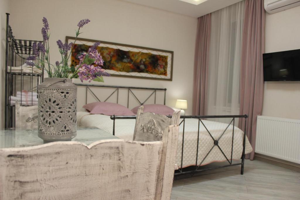 1 dormitorio con 1 cama con un jarrón de flores sobre una mesa en Centre Apartment on Rustaveli av., en Tiflis