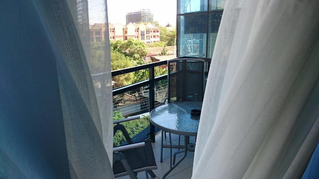 uma varanda com uma mesa e cadeiras e uma janela em Yaya Brooks - Tomax em Nairobi