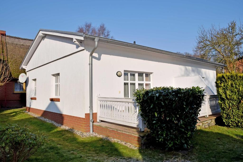 ein weißes Haus mit einem Balkon auf einem Hof in der Unterkunft Ferienwohnungen Fiete & Ole in Ostseebad Sellin