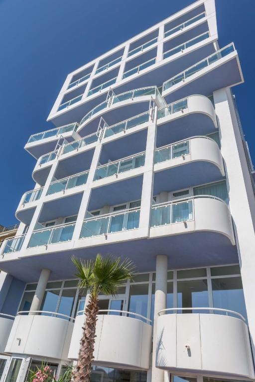 a tall building with a palm tree in front of it at Hotel Mediterraneo in Sottomarina