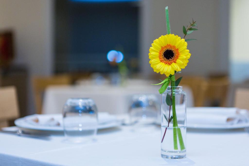 a vase with a sunflower in it on a table at Hotel Mediterraneo in Sottomarina