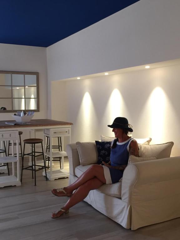 a woman sitting on a couch in a living room at Arli Hotel Hideaway Punta Ala - Adults Only in Punta Ala
