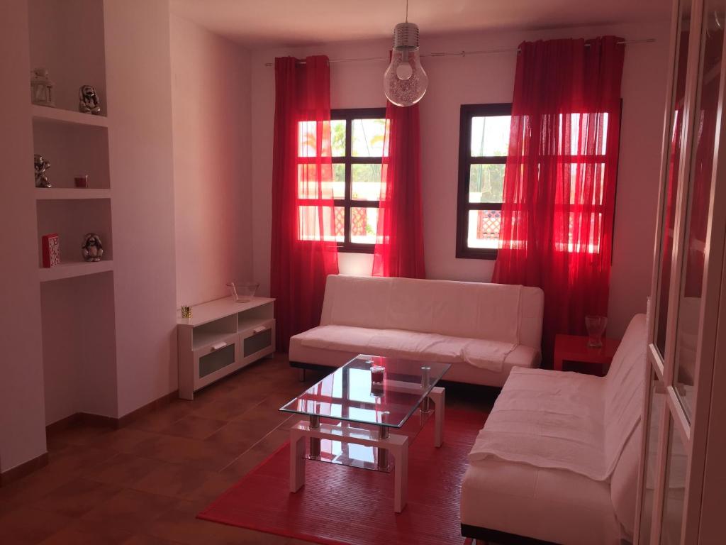 een woonkamer met rode gordijnen en een witte bank bij Playa Granada Golf in Motril