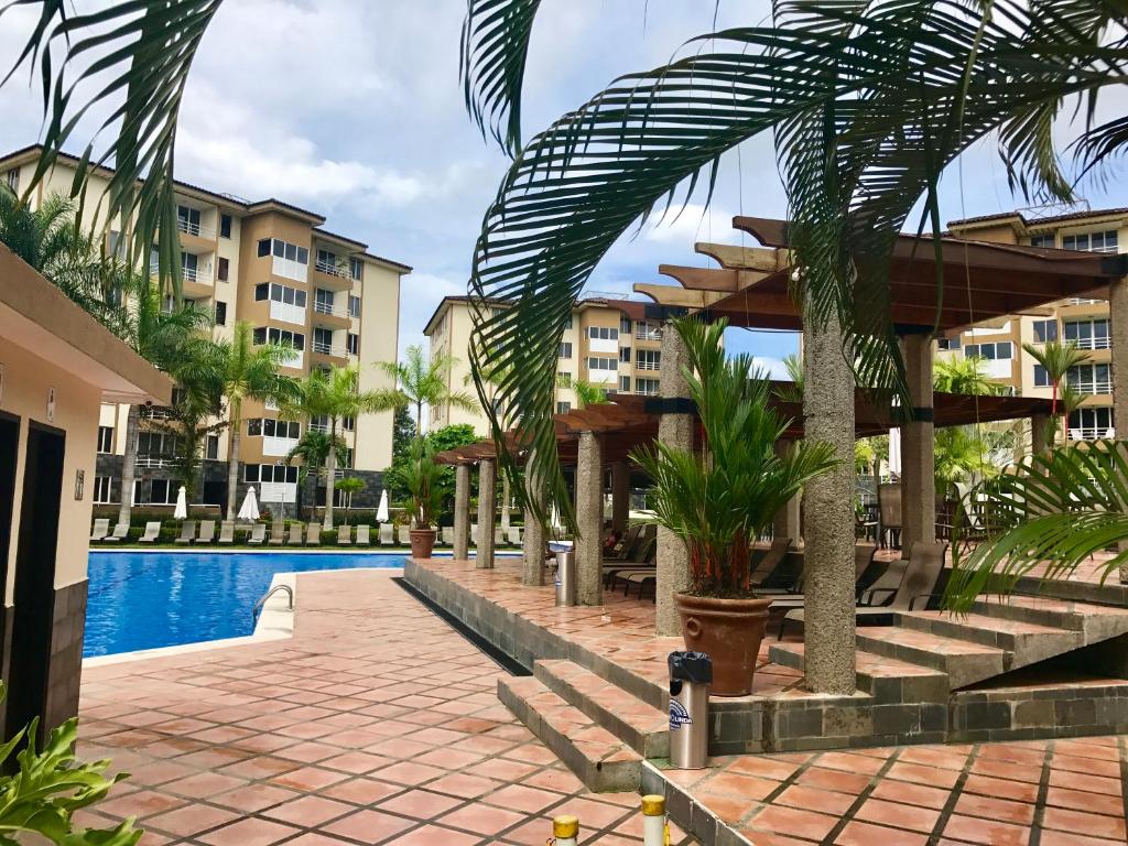 un complejo con piscina, palmeras y edificios en Jaco Beach Penthouse, en Jacó