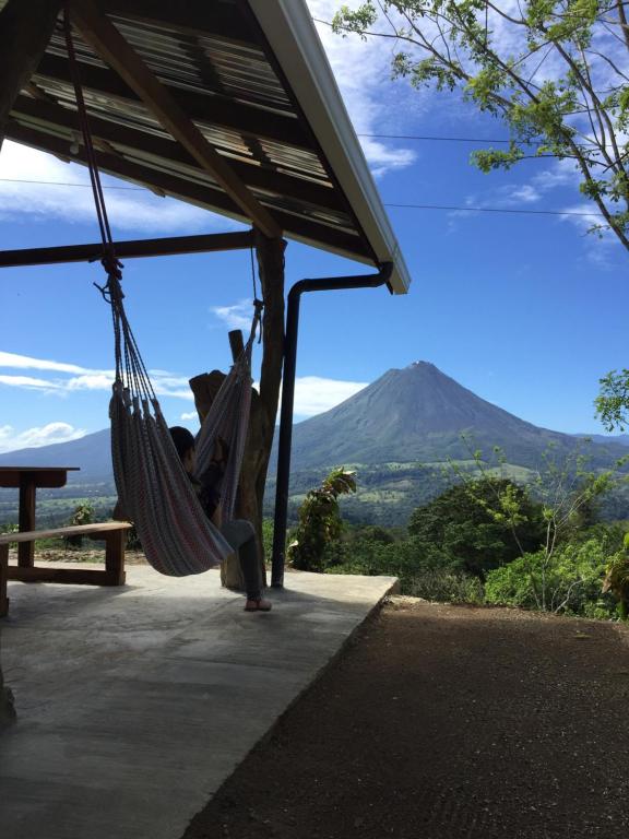 a woman sitting in a hammock with a mountain in the background at Casa Torre Eco- Lodge in Fortuna