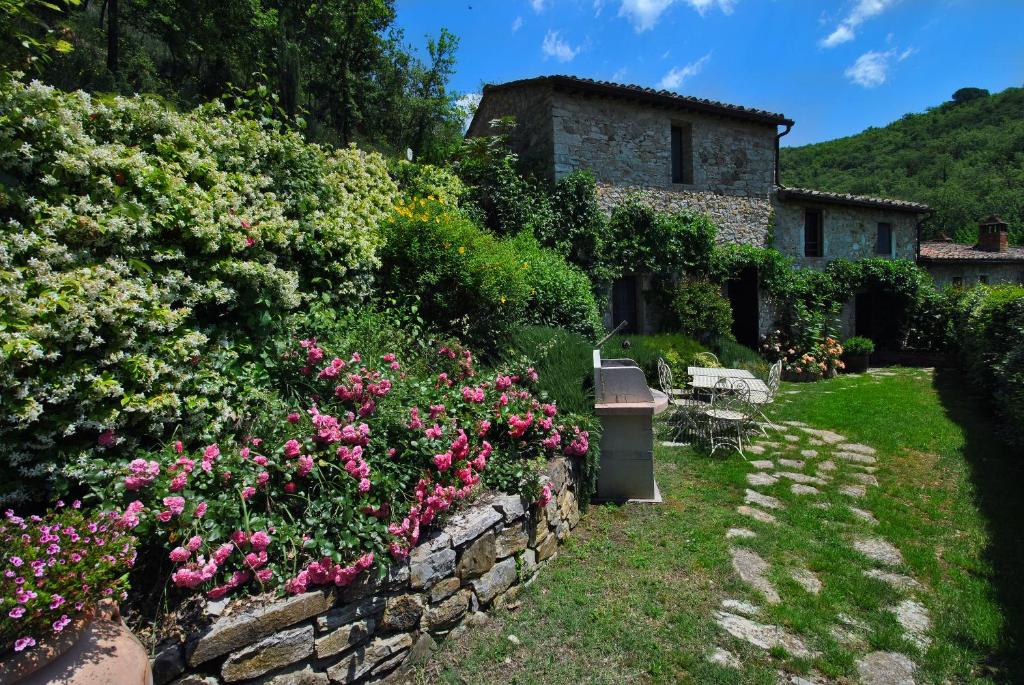un jardín con flores y una pared de piedra en Molino di Bombi, en Castellina in Chianti