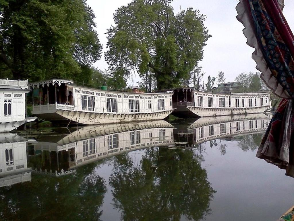 a reflection of buildings in a body of water at Butts Clermount Houseboat in Srinagar