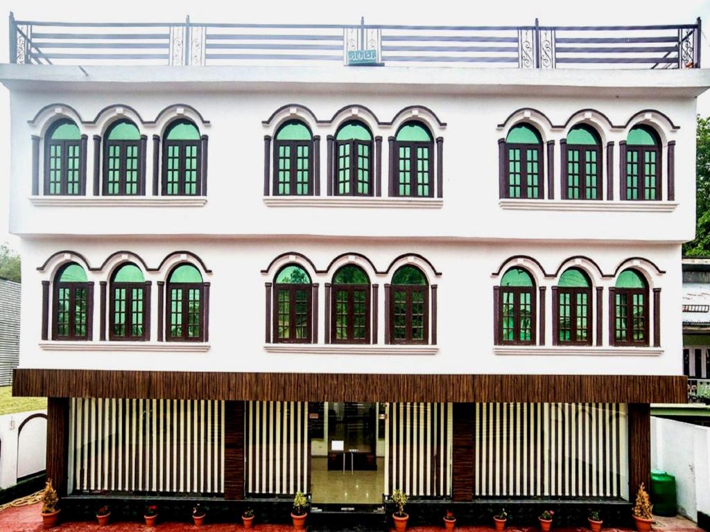 a large white building with green windows at Hotel Ash Vale in Srinagar