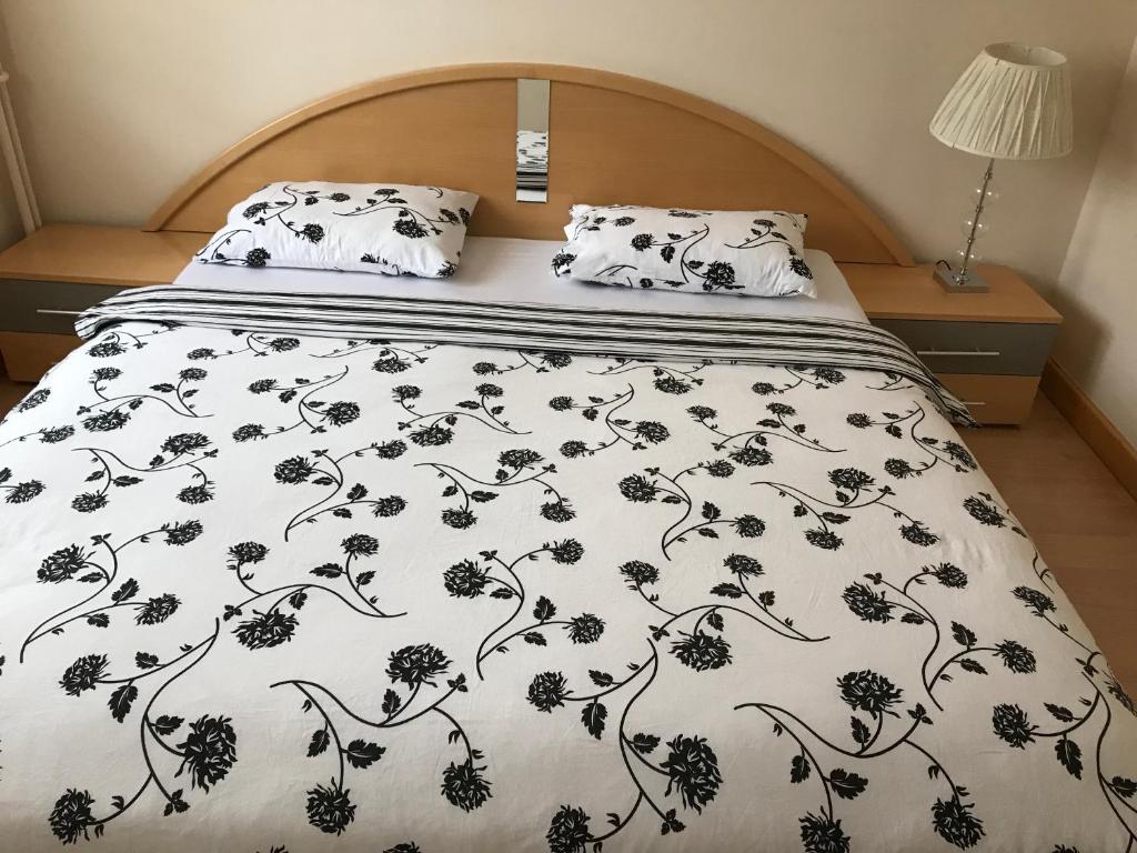 a bed with a black and white blanket and pillows at Boulevard Apartment in Oradea